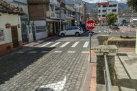 a street that has a stop sign on it with cars parked along the side of the road