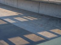 a skateboarder riding on a cement ramp next to a city street under a bridge