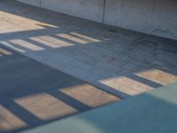 a skateboarder riding on a cement ramp next to a city street under a bridge