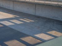 a skateboarder riding on a cement ramp next to a city street under a bridge