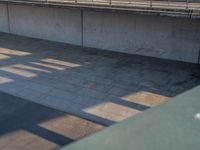 a skateboarder riding on a cement ramp next to a city street under a bridge