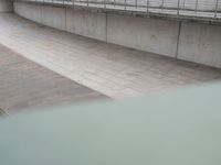 a boy on a skateboard doing tricks in an outdoor setting on a walkway between two concrete walls