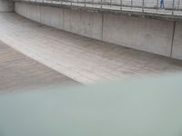 a boy on a skateboard doing tricks in an outdoor setting on a walkway between two concrete walls