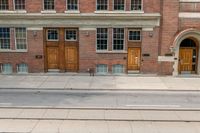 a red fire hydrant is sitting in front of a brick building and doors on the corner