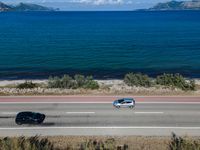 an empty road with a view of a lake and mountains in the distance, with a motorcycle parked near by the front