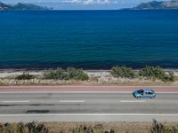 an empty road with a view of a lake and mountains in the distance, with a motorcycle parked near by the front