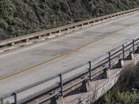 people ride their motorcycle on the bridge as others watch from above it, along with their bikes