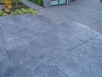 a concrete patio with black and white patterned patterning and trees on either side of it