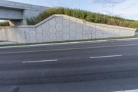 a concrete ramp is built on the side of a roadway near an overpass bridge