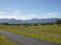 a dirt road next to the water on a hill in australia with mountains in the background