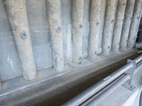 a row of pipes with wires running up them next to a drain system in a stone wall