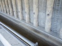 a row of pipes with wires running up them next to a drain system in a stone wall