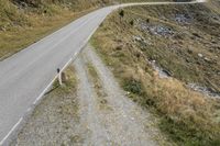 a motorcycle parked on a small mountain side road near mountains with no cars driving on it