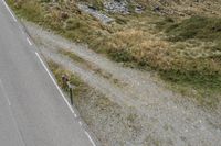 a motorcycle parked on a small mountain side road near mountains with no cars driving on it