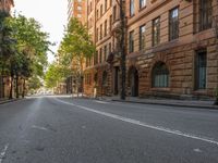 a street with many trees and some buildings along the sides of it with a person on the street at the right