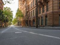 a street with many trees and some buildings along the sides of it with a person on the street at the right