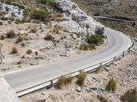 a person rides an empty, long bike near a road and cliff formation on a sunny day