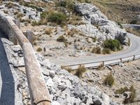 a person rides an empty, long bike near a road and cliff formation on a sunny day