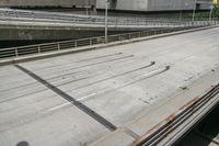 a paved highway overpass with traffic signals and metal fencing surrounding it with buildings, a man in the distance