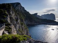 a small boat is docked near the shore of a cliff overlooking the sea with a light on it