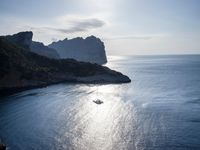a small boat is docked near the shore of a cliff overlooking the sea with a light on it