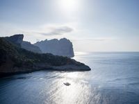 a small boat is docked near the shore of a cliff overlooking the sea with a light on it