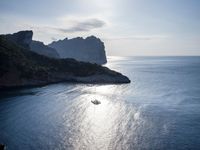 a small boat is docked near the shore of a cliff overlooking the sea with a light on it