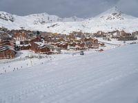 a city with lots of people skiing down the snow covered ground in the mountains in the winter