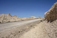 a dirt road going through a wide sandy area with rocks and boulders on both sides