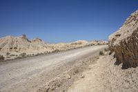 a dirt road going through a wide sandy area with rocks and boulders on both sides