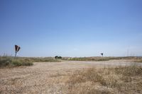 an empty open lot in a rural part of the world in the desert with two rusty road signs