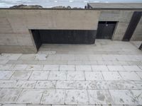 a long concrete building overlooking the ocean near the beach has a door that leads to the room in which there is a closed area