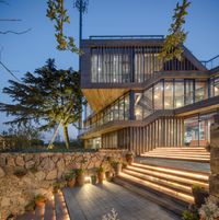 an outdoor staircase is lit up with lights and plants in front of the house, while a wall of windows stands at the bottom