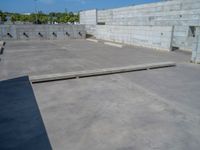 the empty parking lot in front of a wall with apartment buildings on it and a skateboarder on a ramp