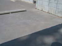 the empty parking lot in front of a wall with apartment buildings on it and a skateboarder on a ramp