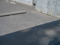 the empty parking lot in front of a wall with apartment buildings on it and a skateboarder on a ramp