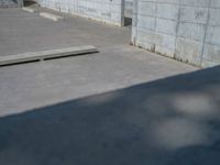 the empty parking lot in front of a wall with apartment buildings on it and a skateboarder on a ramp