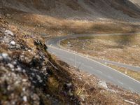 a motorcycle is traveling down a scenic mountain road on the side of a large hill