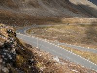 a motorcycle is traveling down a scenic mountain road on the side of a large hill