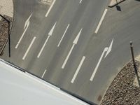 an overhead view of a street with cars passing by with arrows drawn down the road