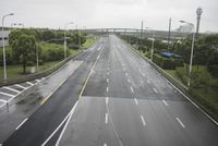 an empty highway with traffic lights on both sides and trees in the background a gray overcast sky has overcast and overcast skies above