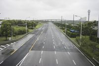an empty highway with traffic lights on both sides and trees in the background a gray overcast sky has overcast and overcast skies above