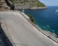 a paved road beside some large boats and a bridge with a bridge to the water