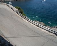 a paved road beside some large boats and a bridge with a bridge to the water