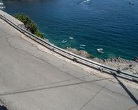 a paved road beside some large boats and a bridge with a bridge to the water