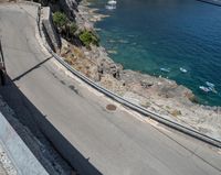 a paved road beside some large boats and a bridge with a bridge to the water