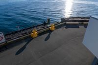 the view of a calm blue ocean and the sun reflecting on the water from the bow of a large boat