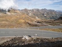 a paved road near mountains, with signs on it, in the mountains in the sun