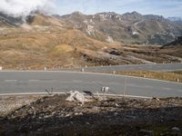 a paved road near mountains, with signs on it, in the mountains in the sun