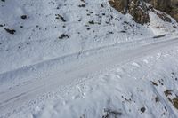 an aerial view of the snow covered road leading to the mountains and a person riding a skis